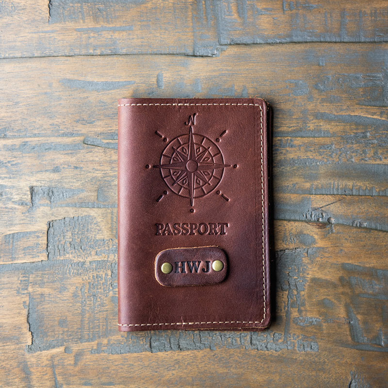 Outside of fine leather passport cover features a compass design and personalized initials; inside of passport cover features two pockets