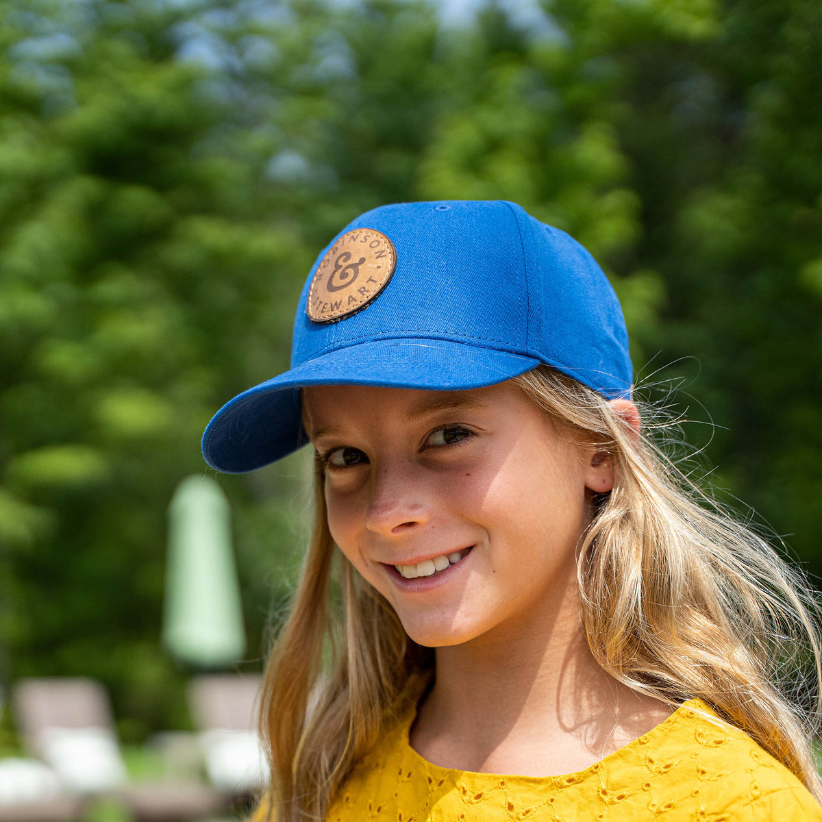 Child wearing a blue 6 panel OTTO baseball cap with a custom leather patch