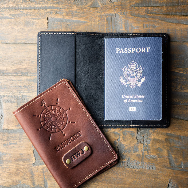 Outside of brown fine leather passport cover with compass imprint and personalized initials; inside of black leather passport cover