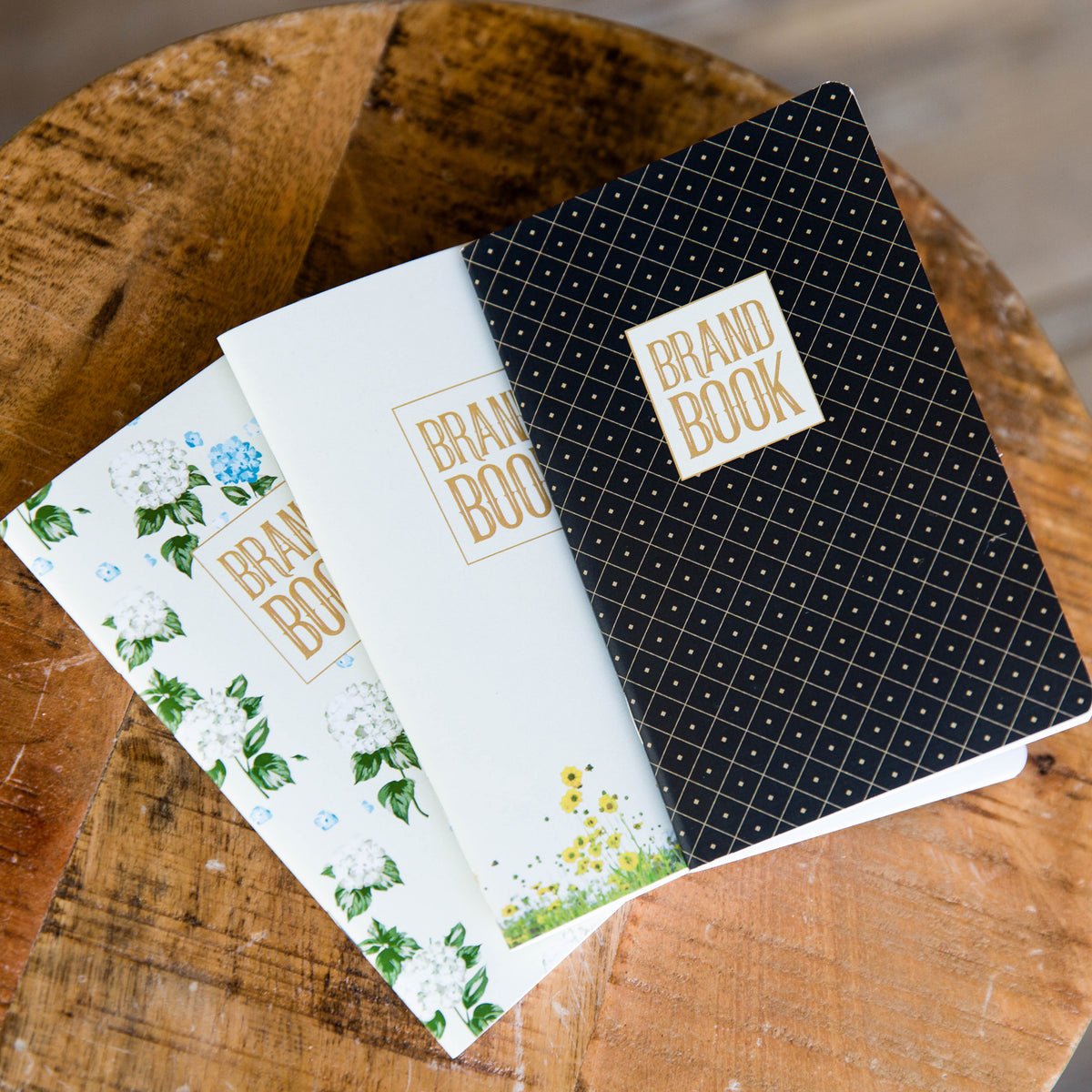 Three brand book notepads; one is black; one has flowers at the bottom; one is covered in a floral pattern