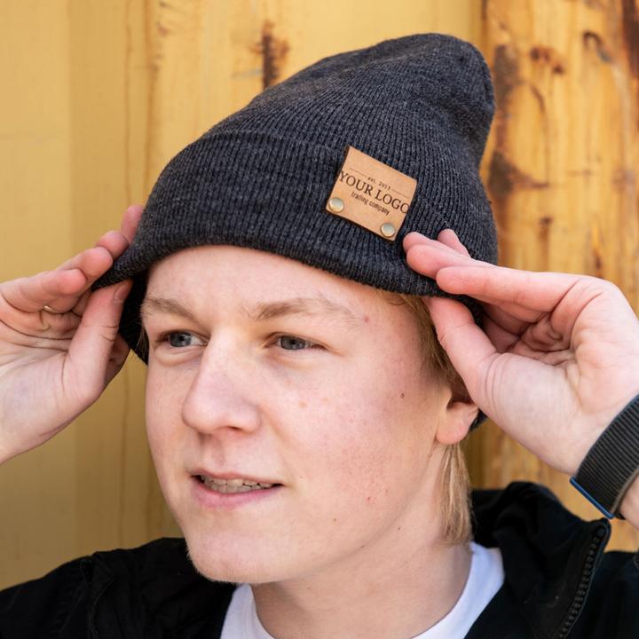 Person wearing heather beanie with custom logo leather patch
